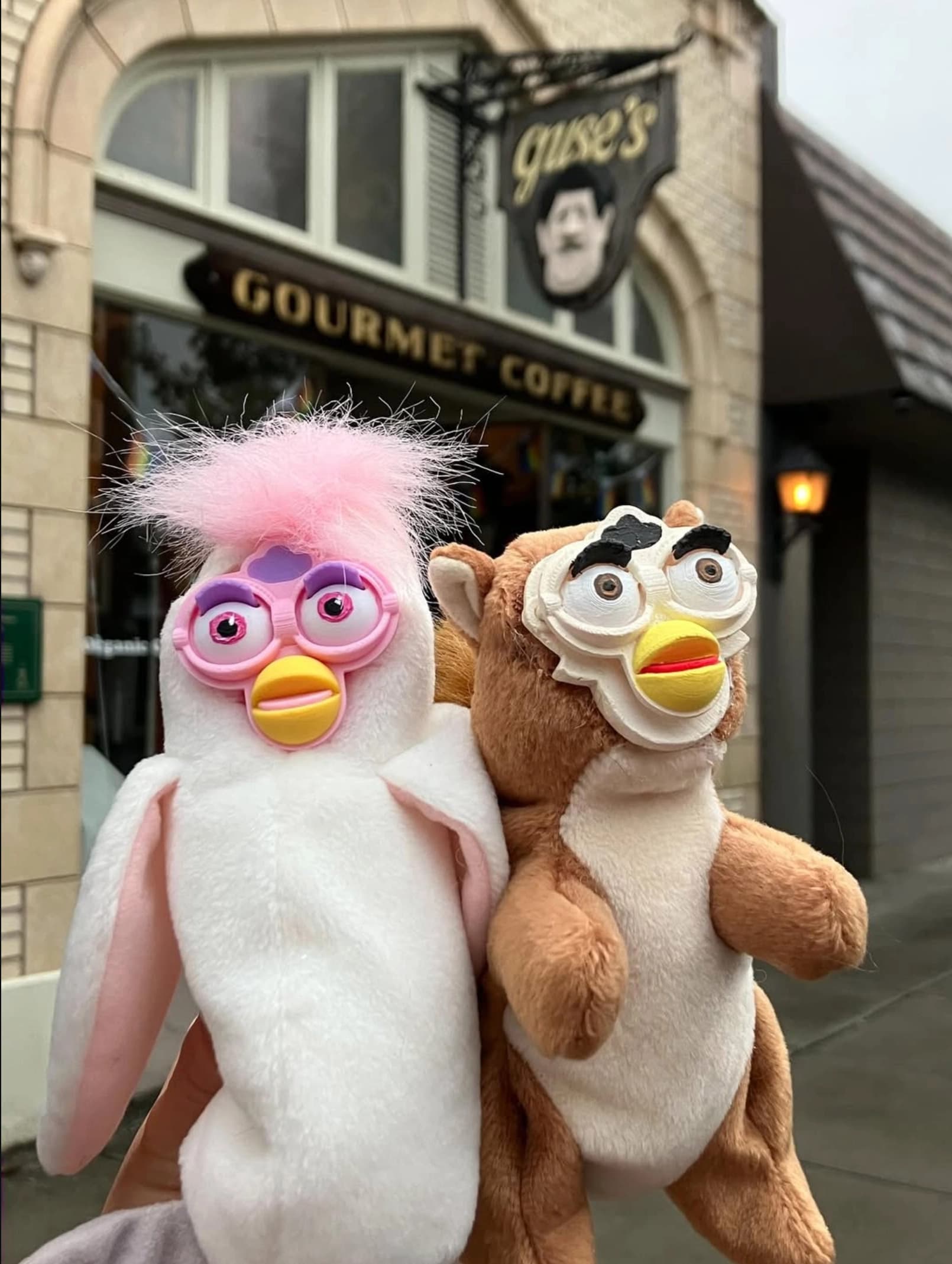 Two upcycled Beanie Babies with custom sculpted Furby faces held up outside a Longview coffee shop Cafe Guse, by artist Jen Milliren